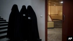 FILE - Women stand outside an auditorium at Kabul University's education center in Kabul, Afghanistan, Sept. 11, 2021. 