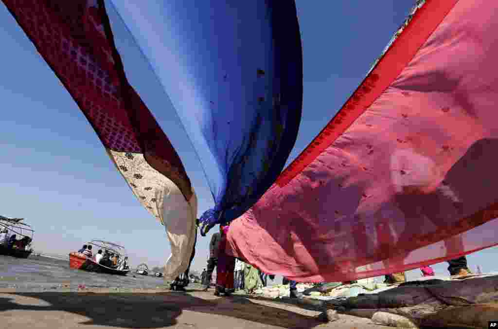 Hindu devotees dry their clothes after taking a dip at Sangam, the confluence of rivers Ganges, Yamuna, and mythical Saraswati during the Hindu festival of Shivaratri, that also marked the last day of the annual traditional fair of Magh Mela, in Allahabad, India.