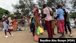 Maimouna avec son sachet de savons au milieu de clients potentiels à Dakar, le 10 août 2020. (VOA/Seydina Aba Gueye)