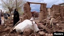 A woman stands next to her house destroyed by flood in Enjil district of Herat province, Afghanistan, March 29, 2019.