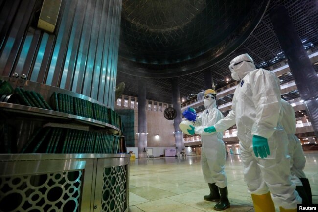 Para petugas melakukan penyemprotan disinfektan untuk mencegah perebakan virus corona di Masjid Istiqlal di Jakarta.
