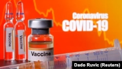 醫用注射器附近的小瓶子標籤上寫著“疫苗”字樣。橘黃色背景上有“冠狀病毒COVID-19”字樣。（2020年4月10日）
