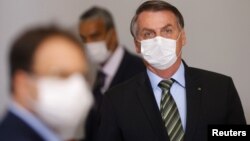 Le président brésilien Jair Bolsonaro portant un masque avant une conférence de presse pour annoncer des mesures judiciaires fédérales visant à freiner la propagation du coronavirus, Brasilia, 18 mars 2020. (Reuters/Adriano Machado)