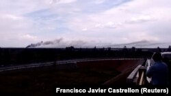 A person watches as smoke billows above a site where an Aeromexico-operated Embraer passenger jet crashed in Mexico's northern state of Durango, July 31, 2018, in this still image taken from a video obtained from social media.