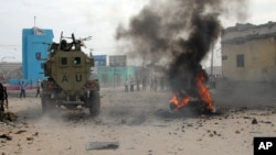 FILE - African Union Mission in Somalia (AMISOM) troops ride an armored vehicle past a burning car after it exploded in Somalia's capital, Mogadishu, Dec. 6, 2011.
