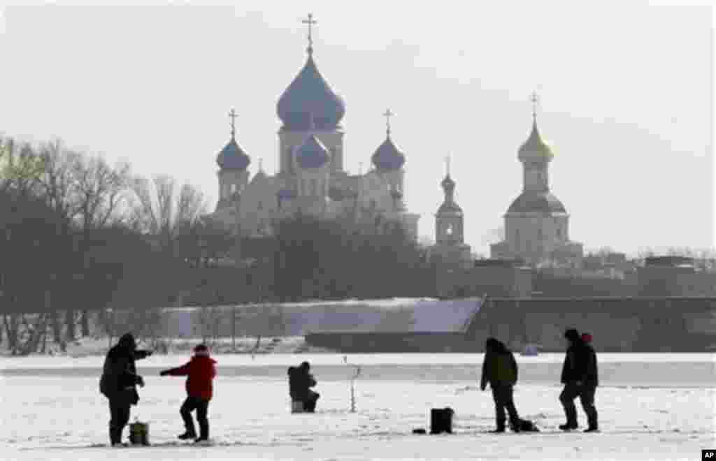 Fishermen gather during ice fishing on the frozen Moskva River with the St. Nicholas Monastery in the background, in Moscow, Russia, Friday, March 9, 2012. Ice fishing, when anglers try to catch fish through a hole in the ice, is very popular in Russia. (