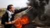 A Palestinian demonstrator hurls stones at Israeli troops during clashes at a protest demanding the right to return to their homeland, at the Israel-Gaza border east of Gaza City, April 6, 2018.