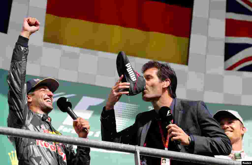 Former Formula One driver Mark Webber of Australia drinks champagne from the shoe of Red Bull&#39;s Daniel Ricciardo of Australia (L) while Mercedes&#39; Nico Rosberg of Germany (R) looks on after the Belgian F1 Grand Prix.