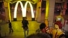一个中国男子在中国东北辽宁沈阳一个火车站的麦当劳快餐店外摆姿态跟麦当劳的吉祥物拍照（资料照片）。
