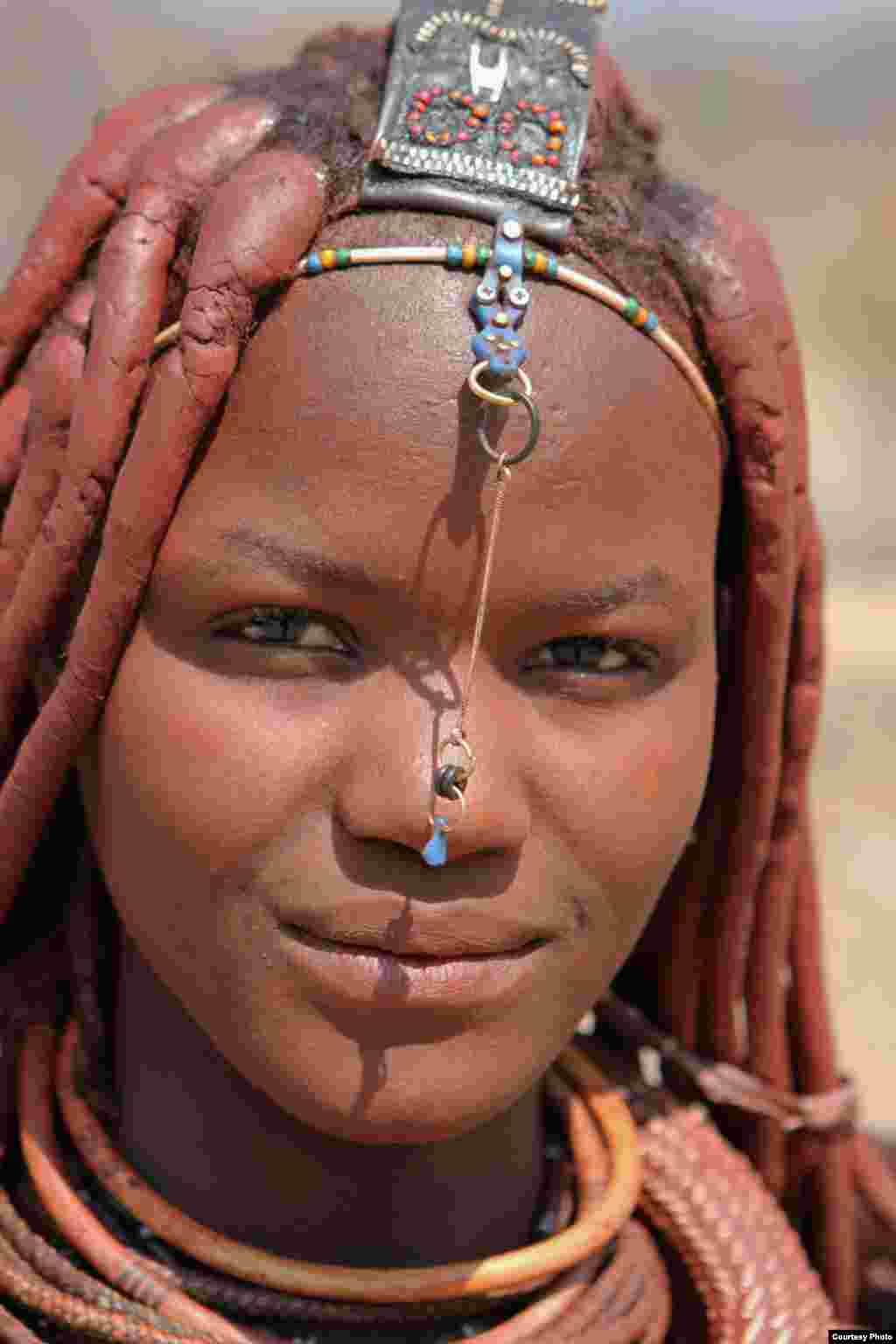 A young Himba girl smiles for a photo in northern Namibia near the Angola border (Jeff Leach/Namibia/VOA reader)