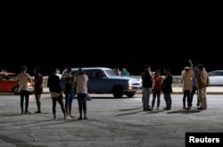 People stand on the seafront boulevard El Malecon in Havana, Cuba, following the announcement of Fidel Castro's death, November 26, 2016.