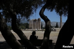 Un turista se sienta a la sombra de un árbol durante un día caluroso, en el sitio arqueológico del Templo de Zeus en Atenas, Grecia, el 4 de julio de 2019. ERRORES / Costas Baltas