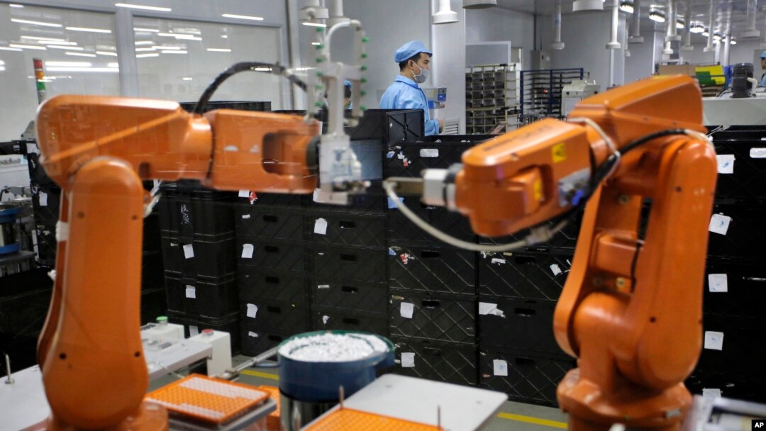 FILE - A Chinese worker is seen behind robotic arms at a technology factory in Shenzhen, southern China, Aug. 21, 2015. China is spearheading a campaign for openness fearing that Chinese exporters could otherwise face stiffer resistance in Western countries.