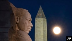 The rising full moon passes behind the Martin Luther King Memorial and the Washington Monument, Tuesday evening, Dec. 29, 2020, in Washington. (AP Photo/J. David Ake)