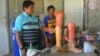 Kyaw Win and his colleague, both former Karenni fighters who lost legs to landmines, look at prosthetic legs in their workshop in Loikaw. (P. Vrieze/VOA)