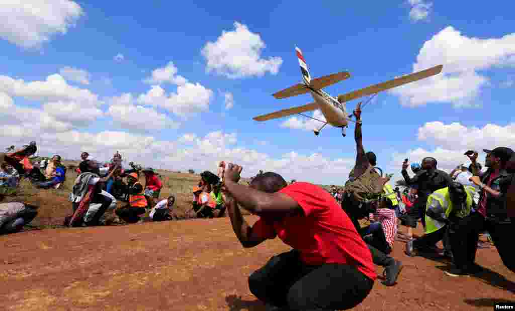 Spectators react as a plane flies over them during the Vintage Air Rally at the Nairobi national park in Kenya&#39;s capital Nairobi.