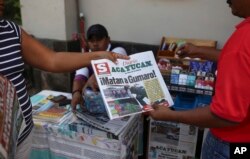A man buys a newspaper carrying the Spanish headline "They killed Gumaro!" on the sidewalk in Acayucan, Veracruz state, Mexico, Dec. 20, 2017.