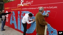 People take condoms from billboard on World Aids Day, Athens, Dec. 1, 2011.