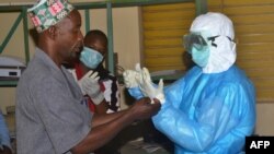 Para pekerja membuka baju pelindung dari virus Ebola setelah jam kerja mereka selesai di sebuah rumah sakit di Guinea (25/8/2014). 