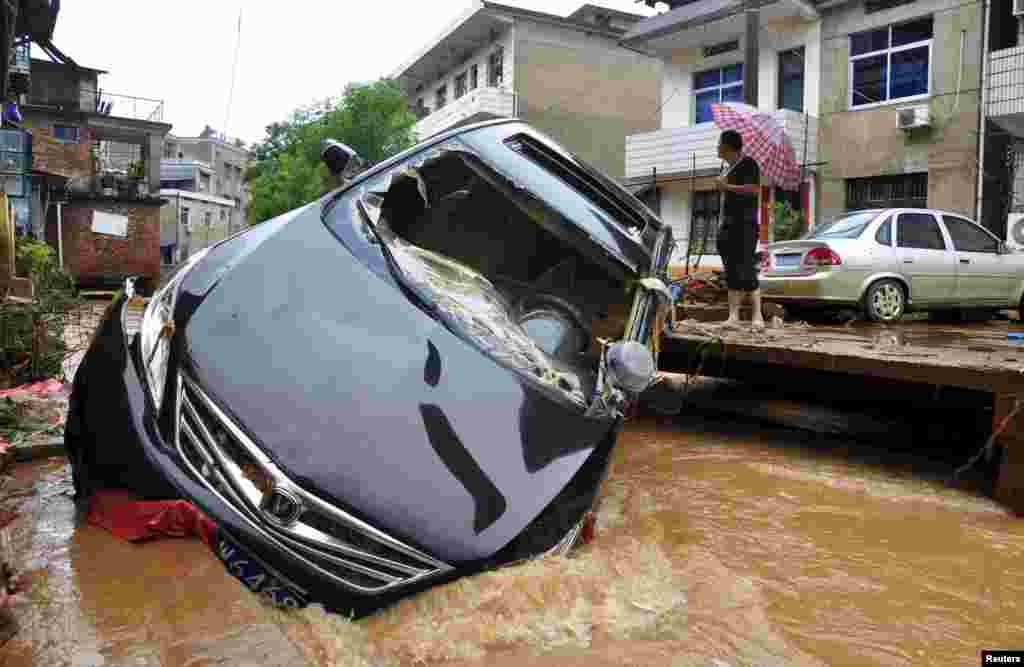 Um carro está preso num rio que galgou as margens após a chuva violenta em Dexing, província de Jiangxi, China. Junho 3, 2015