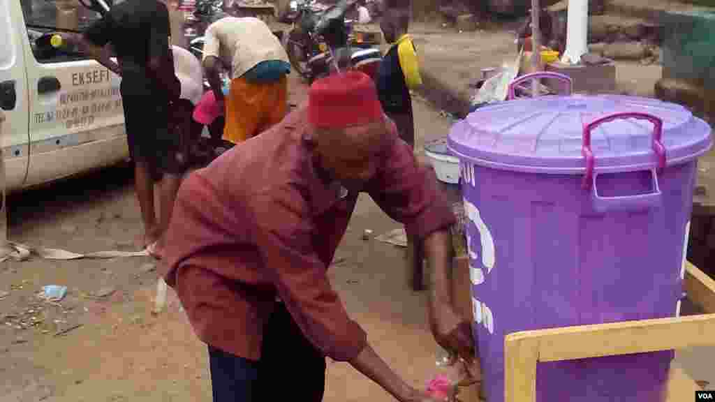 Cet homme se lave les mains en plein marché. La sensibilisation pour une hygiène de tous est nécessaire pour contrer Ebola. (AP Photo). 