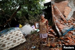 FILE - Maria Guzman, 70, a housewife, stands amid the rubble of her house after an earthquake in San Jose Platanar, at the epicenter zone, Mexico, Sept. 28, 2017.