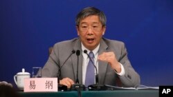 FILE - China's Central Bank Governor Yi Gang gestures as he speaks during a press conference on the sideline of the National People's Congress at the media center in Beijing, March 10, 2019.