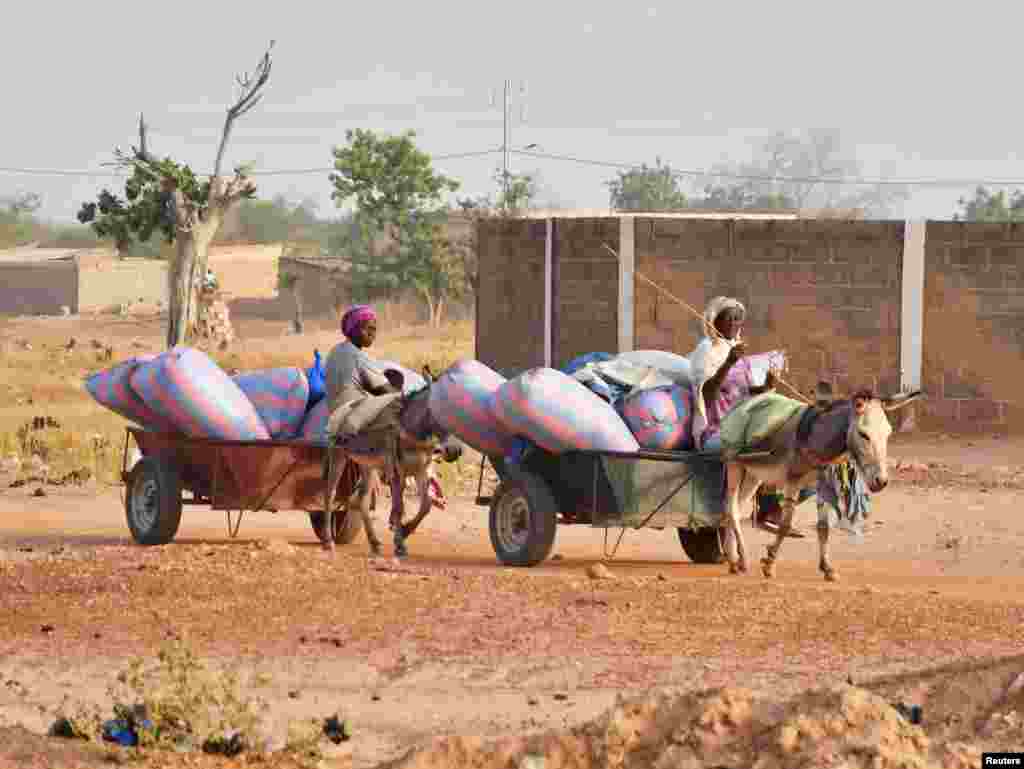 Displaced women, who fled from attacks of armed militants in town of Roffenega, ride donkey carts loaded with food aid at the city of Pissila, Burkina Faso.