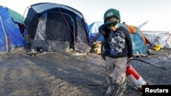 A young migrant pulls a fire extinguisher in a muddy field at a camp of makeshift shelters for migrants and asylum-seekers from Iraq, Kurdistan, Iran and Syria, called the Grande Synthe jungle, near Dunkirk, France, January 25, 2016. 