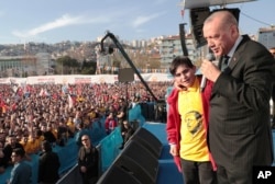 Turkey's President Recep Tayyip Erdogan reacts with a boy as he addresses the supporters of his ruling Justice and Development Party during a rally in Kocaeli, Turkey, March 19, 2019. Ignoring widespread criticism, Erdogan on Tuesday again showed excerpts of a video taken by the attacker who killed 50 people in mosques in New Zealand, to denounce rising hatred and prejudice against Islam.