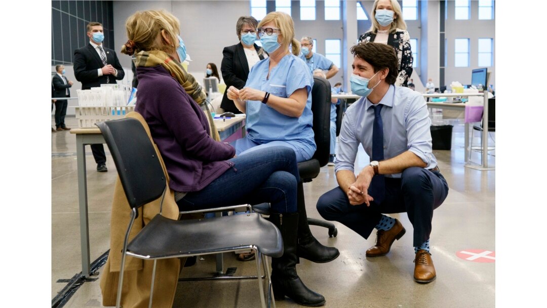 PM Kanada Justin Trudeau berbicara dengan seorang perempuan yang akan divaksinasi COVID-19 di Montreal, 15 Maret 2021. (Paul Chiasson / The Canadian Press via AP)