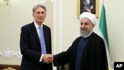 Iran's President Hassan Rouhani (R) welcomes British Foreign Secretary Philip Hammond at the start of their meeting in his office, in Tehran, Iran, Aug. 24, 2015.