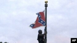 Britanny Newsome of Charlotte, N.C., climbs a flagpole to remove the flag at a Confederate monument in front of the State House in Columbia, S.C., June, 27, 2015. 