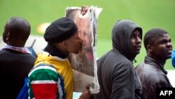 A man kisses the portrait of South African former president Nelson Mandela during his memorial service at the FNB Stadium (Soccer City) in Johannesburg on December 10, 2013.