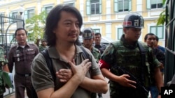 Thailand Politics: FILE - Sombat Boonngam-anong gestures a sign of freedom while arriving at the military court in Bangkok, Thailand, June 12, 2014.