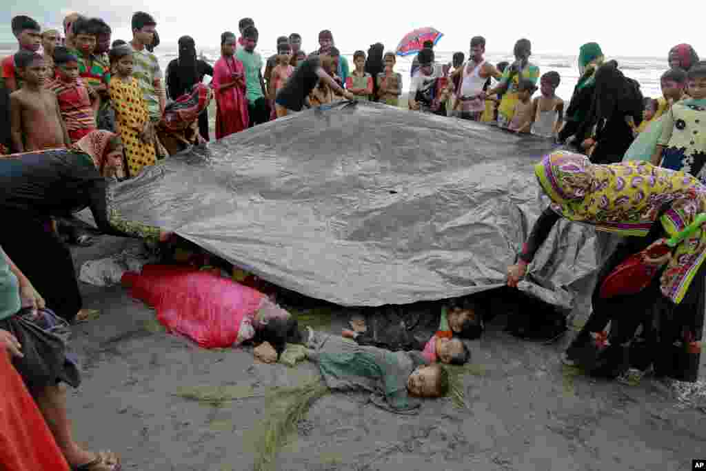 بنگلہ دیش کے ایک سرحدی گاؤں کے رہائشی سرحد عبور کرنے کی کوشش کے دوران ڈوب کر ہلاک ہونے والے روہنگیا عورتوں اور بچوں کی لاشوں کو ڈھانپ رہے ہیں۔