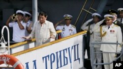 Angkatan Laut Rusia dan seorang perwira Filipina memberi hormat saat Presiden Filipina Rodrigo Duterte turun dari Kapal anti-kapal selam Laksamana Tributs milik Angkatan Laut Rusia di Manila, Filipina, 6 Januari 2017. (AP Photo/Aaron Favila).