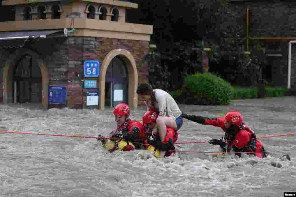 Firefighters rescue a stranded woman on a flooded street, following heavy rainfall in Chengdu, Sichuan province, China, July 11, 2018.