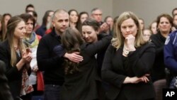 Former gymnast Rachael Denhollander, center, is hugged after giving her victim impact statement during the seventh day of Larry Nassar's sentencing hearing Wednesday, Jan. 24, 2018, in Lansing, Michigan. (AP Photo/Carlos Osorio)