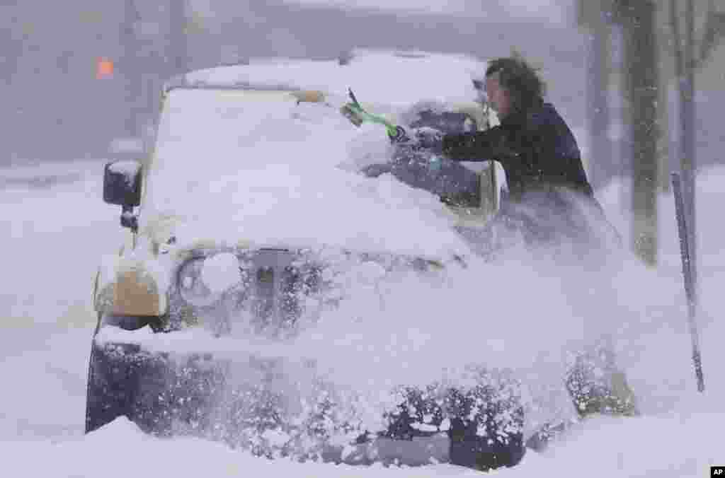 An unidentified motorist clears snow off his four-wheel-drive vehicle in high winds in Denver, Colorado, USA. Forecasters predict that four to 10 inches of snow will blanket Colorado&#39;s eastern plains before the storm, which started Monday in the intermountain West, moves to the east.