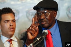 FILE - Alfred Olango's father Richard Olango Abuka, right, with Rev. Shane Harris, left, standing in the back address the news media about the death of Alfred Olango, in San Diego, Nov. 3, 2016.