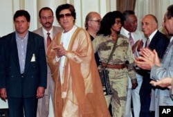 FILE - Libyan leader Muammar Gaddafi (C) arrives at Cairo university for a meeting with university professors, May 27, 1996.