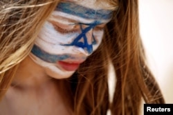 A girl with Israel's national flag painted on her face plays on the beach as part of the celebrations for Israel's Independence Day marking the 70th anniversary of the creation of the state, in Tel Aviv, Israel, April 19, 2018.