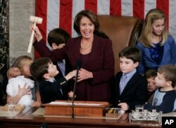 FILE - Newly elected Speaker of the House Nancy Pelosi, holds up the gavel surrounded by children and grandchildren of members of Congress in the U.S. Capitol in Washington, Jan. 4, 2007.