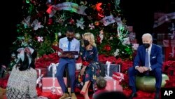 A patient at reads "Olaf's Night Before Christmas" with first lady Jill Biden as President Joe Biden listens at Children's National Hospital in Washington, Dec. 24, 2021.