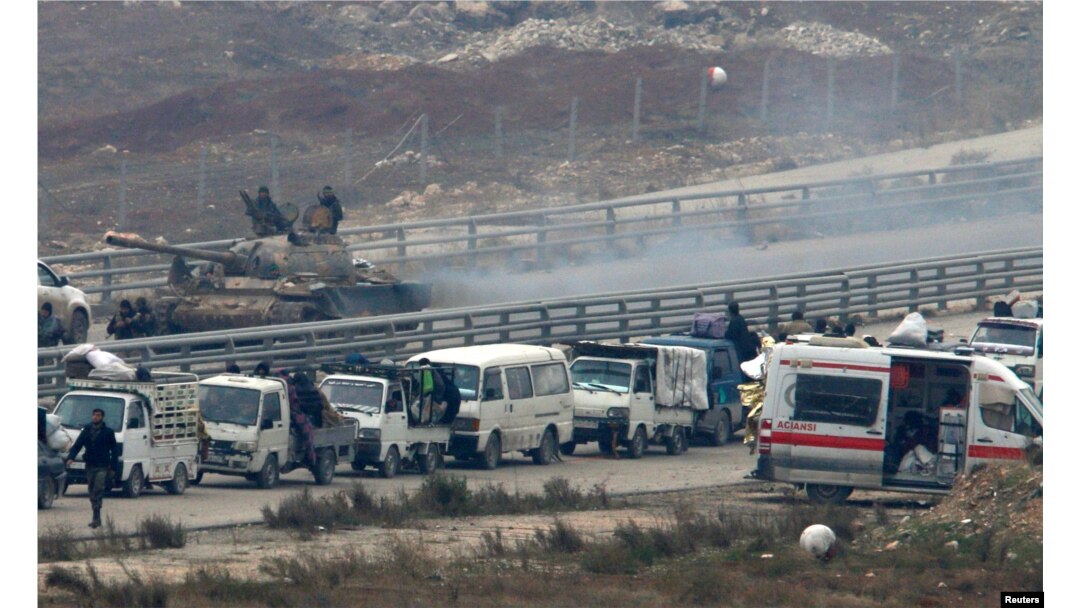 Forces loyal to Syria's President Bashar al-Assad sit on a tank as a convoy of buses and other vehicles bringing people out of eastern Aleppo turns back in the direction of the besieged rebel enclave, Syria, Dec. 16, 2016.