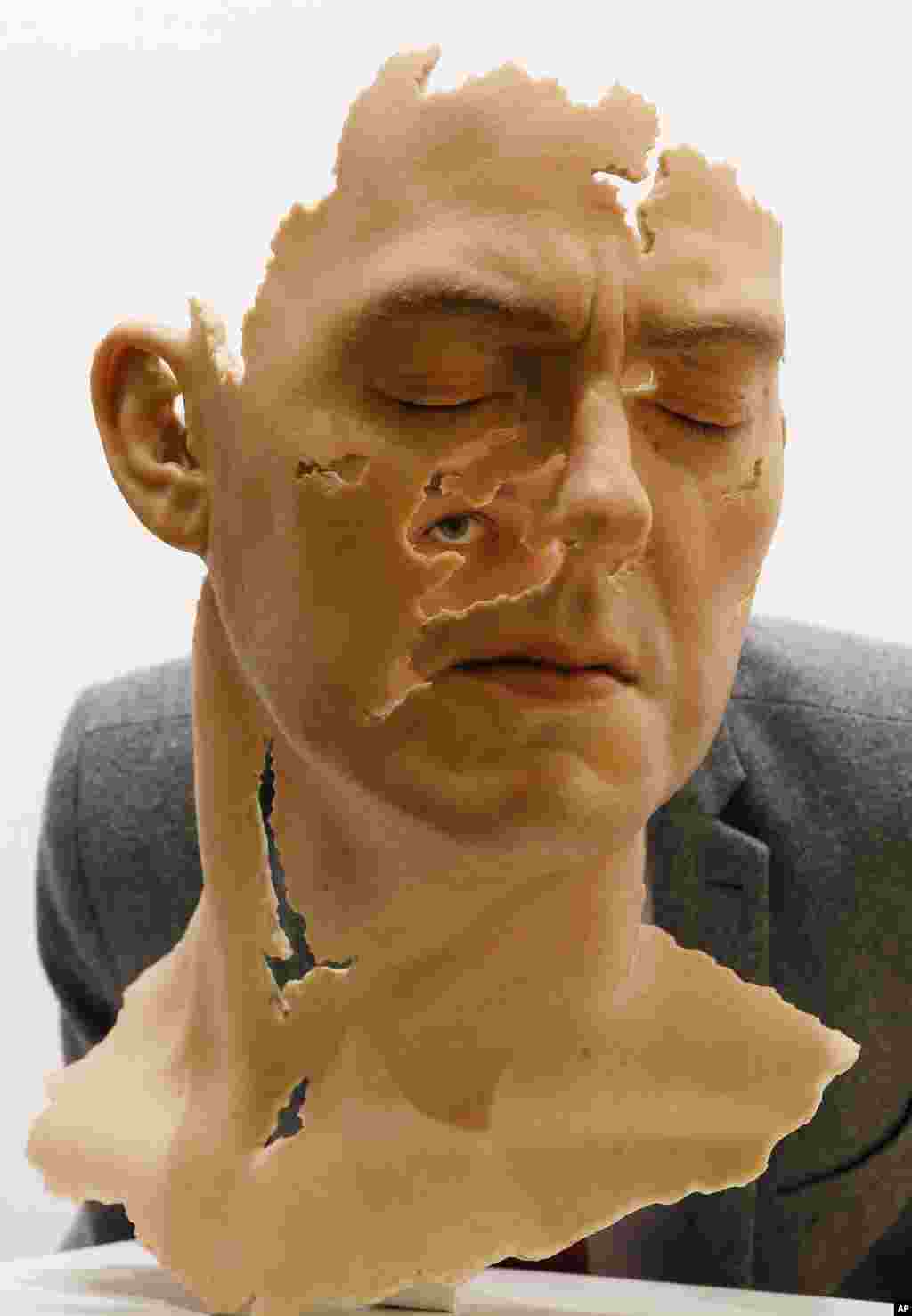 Seorang pengunjung mengintip dari balik patung realis berjudul &quot;Self-Portrait Fragment&quot; karya seniman Jamie Salmon, dalam pameran yang khusus ditujukan bagi media, di ruangan lelang Christie di London, 3 Agustus 2015.