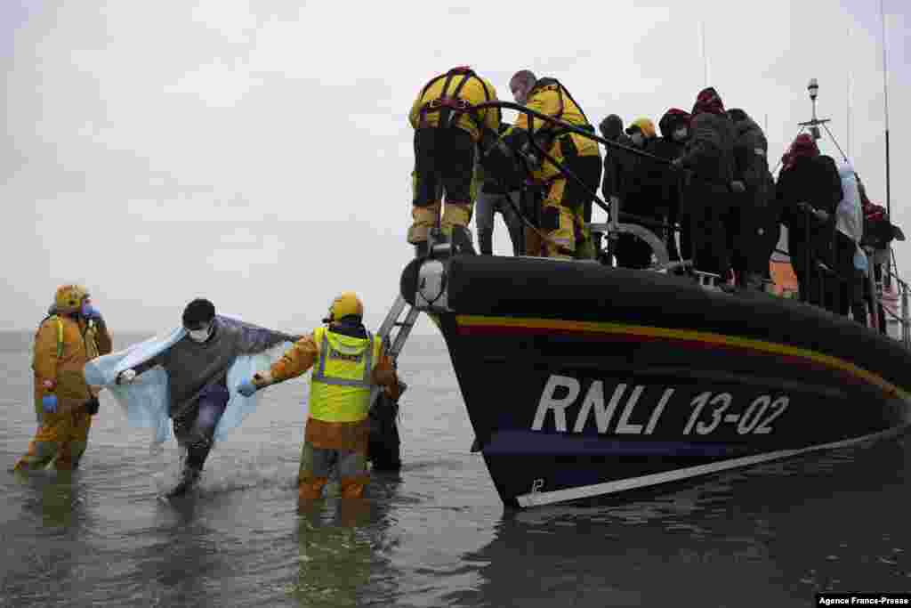 Migrants are helped ashore from a RNLI (Royal National Lifeboat Institution) lifeboat at a beach in Dungeness, on the southeast coast of England, after being rescued while crossing the English Channel.