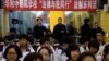 Government workers stand under a banner that reads "Tsinghua-affiliated Chaoyang School, The Law and me together, legal series of talks" as they observe a student meeting on legal matters on Constitution Day in Beijing, Dec. 4, 2014.