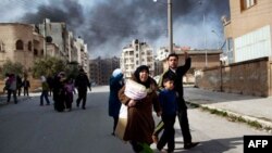 A family escapes from fierce fighting between Free Syrian Army fighters and government troops in Idlib on Saturday